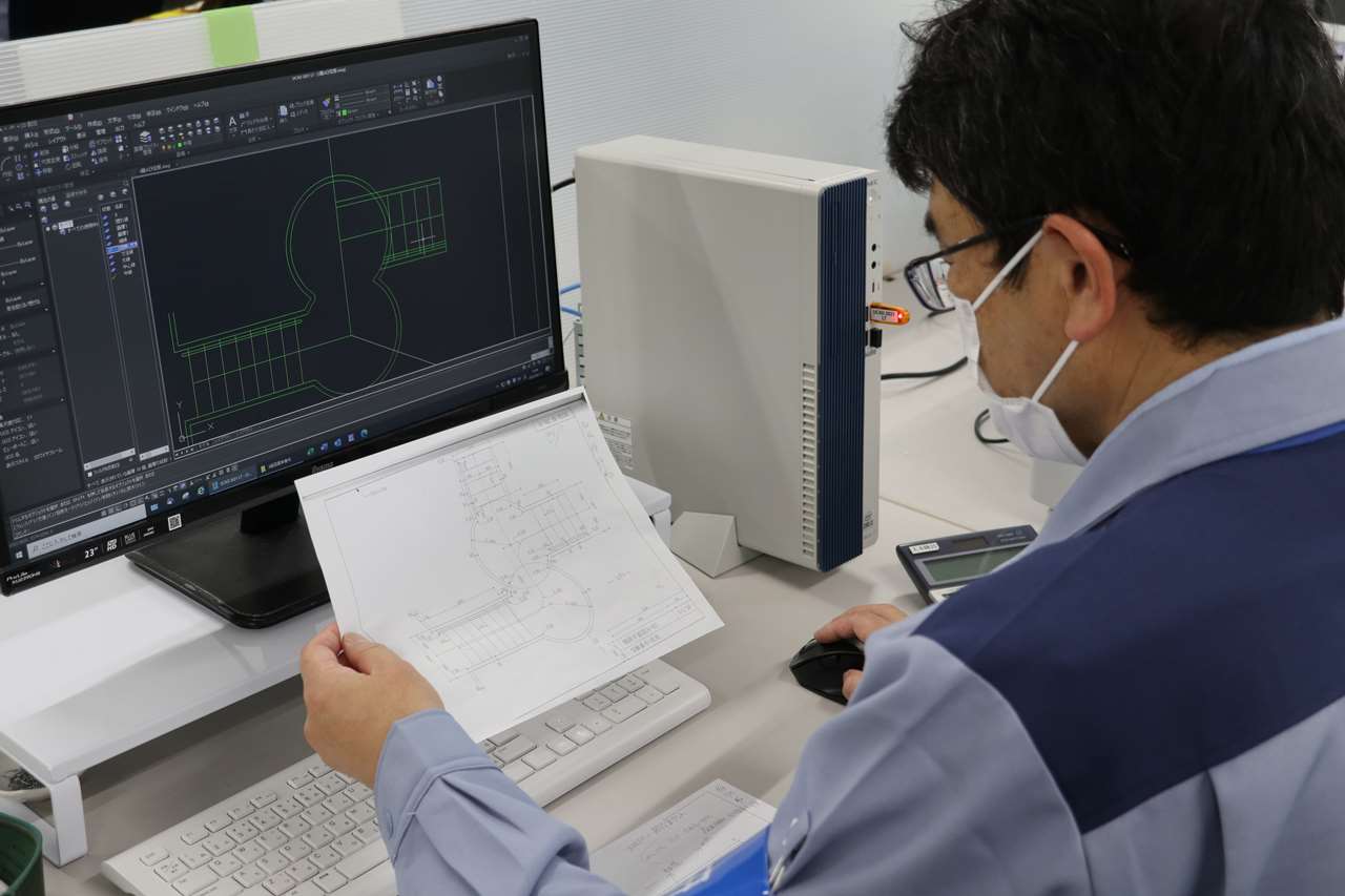 パソコンと書類を照らし合わせている社員